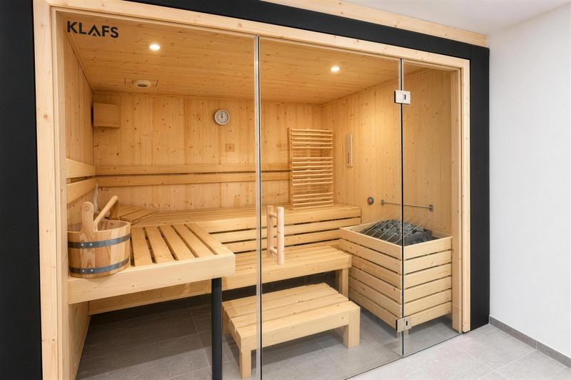 Finnische Sauna aus hellem Holz mit Glasfront und Saunaofen