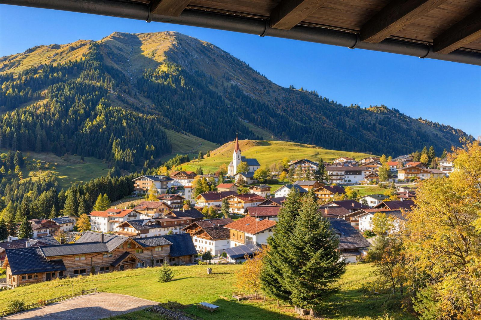 Blick über Berwang mit Kirche, Häusern und Bergen im Herbst