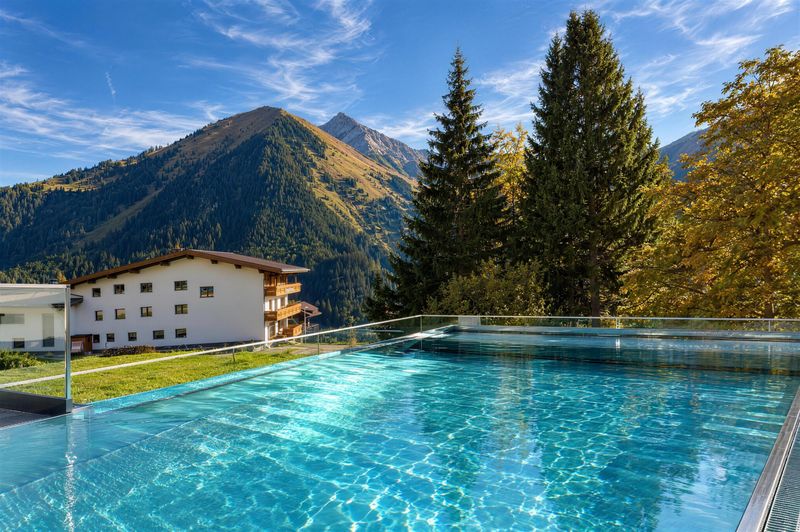 Beheizter Pool mit Glasrand auf der Dachterrasse vor Bergkulisse